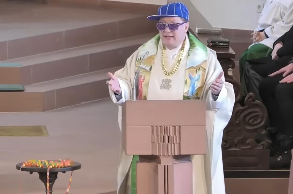 VIDEO: Duhovnik skuša mlade v cerkev privabiti z rapanjem (foto: YouTube/Main-Post/posnetek zaslona)
