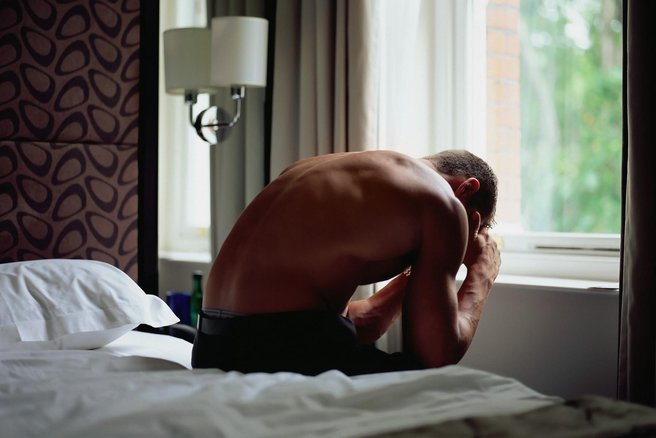 moški v skrbeh sedi na postelji