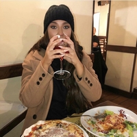 Ženska na večerji pije kozarec vina