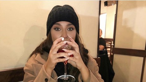 Ženska na večerji pije kozarec vina