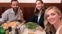 Skupina prijateljev obeduje pizzo v restavraciji.