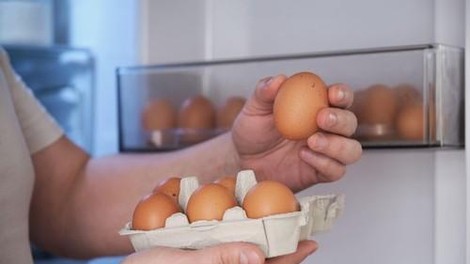 Moški shranjuje jajca v hladilnik.