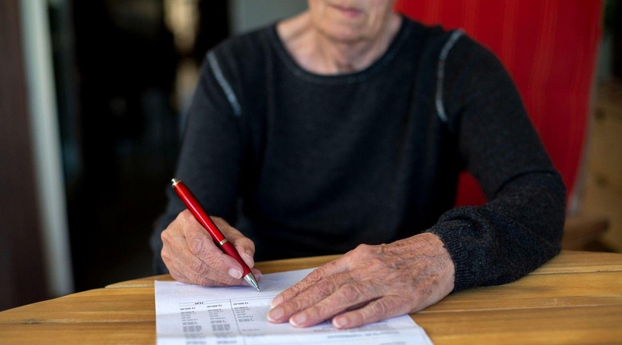 Starejša ženska podpisuje dokument (foto: Profimedia)