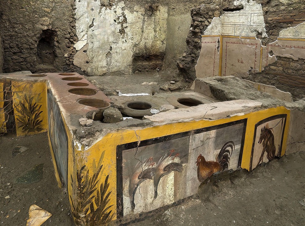 STOJNICA V POMPEJIH Leta 2019 so arheologi med izkopavanji v Pompejih odkrili bogato okrašeno stojnico, poimenovano termopolij, ki spominja na …